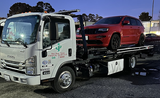 A tow truck with a red car on the back of it