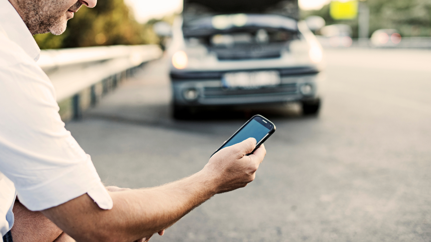 A man is looking at his cell phone on the street